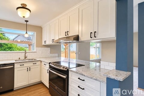 A kitchen with white cabinets and a granite countertop.