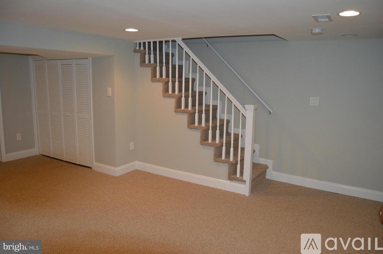 A staircase with white railings and a beige carpeted floor.