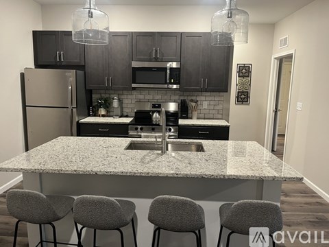 A kitchen with granite countertops and grey barstools.