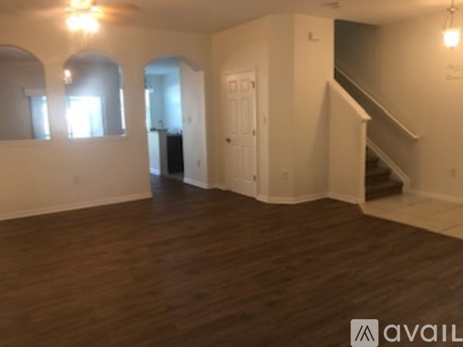 A spacious room with wooden floors and a staircase.
