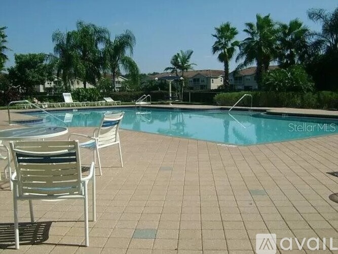 A pool surrounded by chairs and palm trees.
