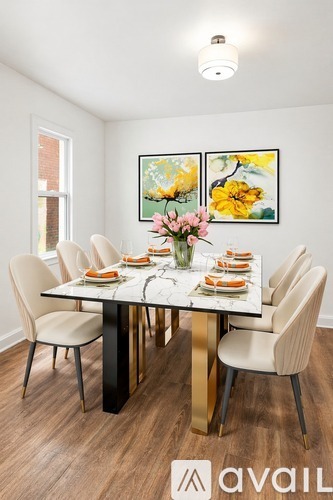 A dining room with a table set for six and a painting on the wall.