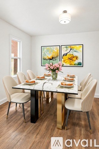 A dining room with a table set for six and a painting on the wall.