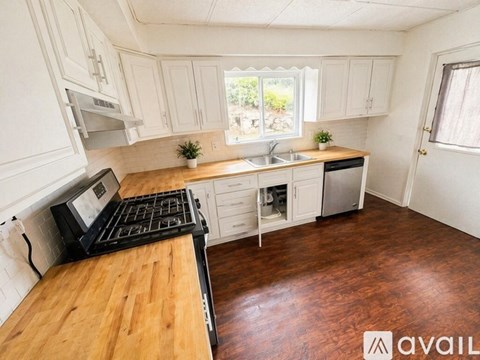 A kitchen with white cabinets and a wooden countertop.