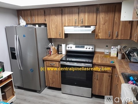 A kitchen with wooden cabinets and a stainless steel refrigerator.