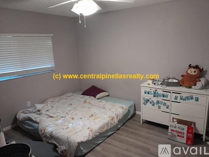A bedroom with a bed, dresser, and a ceiling fan.