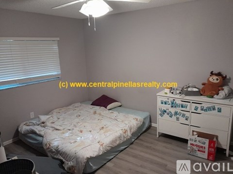 A bedroom with a bed, dresser, and a ceiling fan.