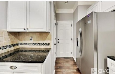 A kitchen with white cabinets and a stainless steel refrigerator.