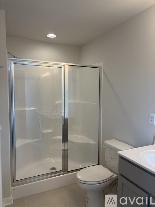 A white toilet sits next to a walk-in shower with a glass door.