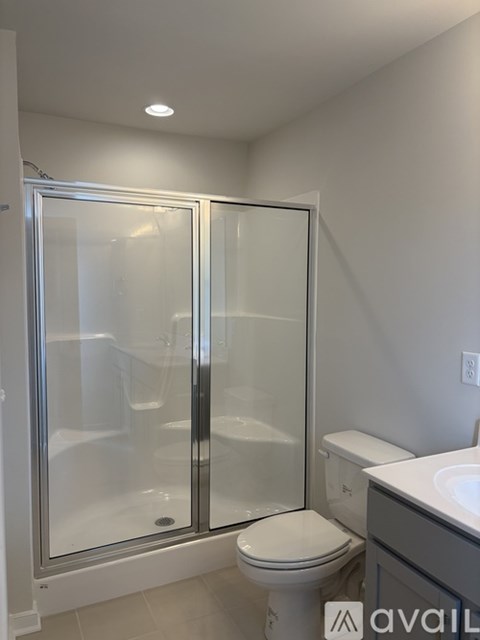 A white toilet sits next to a walk-in shower with a glass door.