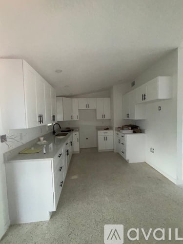 A kitchen with white cabinets and a counter top.