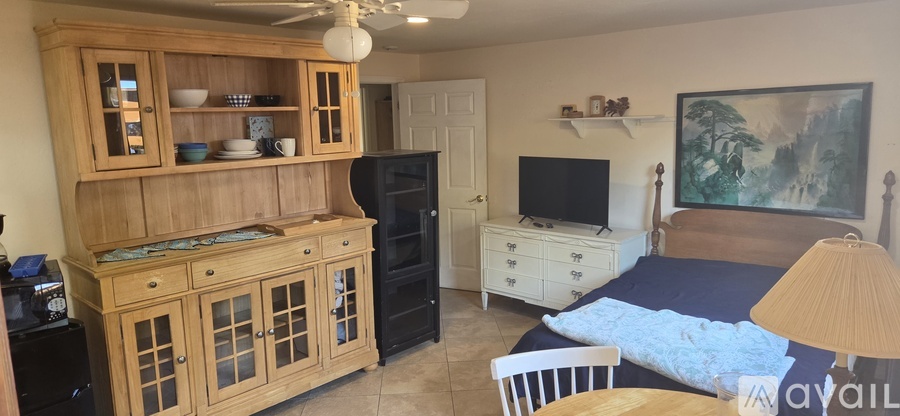 A bedroom with a bed, dresser, and a wooden hutch.