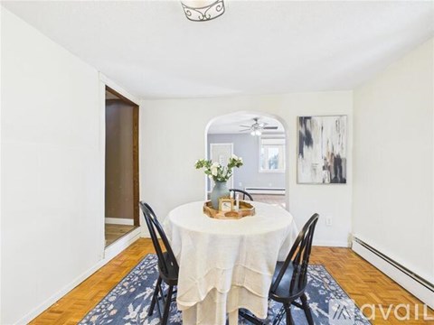 A dining room with a round table covered in a white cloth and four chairs around it.