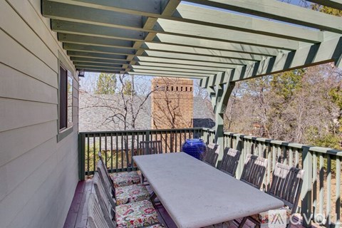 A balcony with a table and chairs overlooking a brick building.