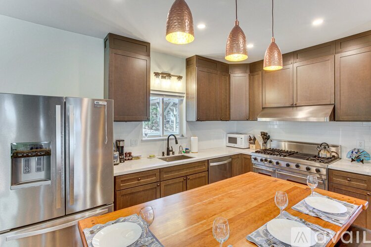 A modern kitchen with a wooden table set for two.