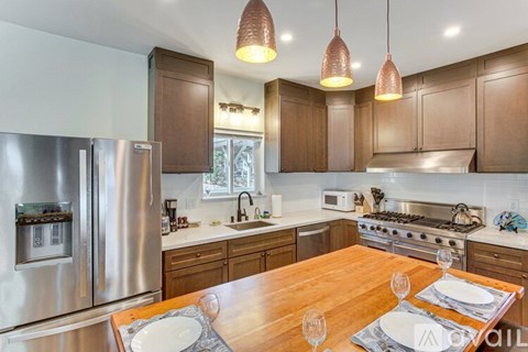 A modern kitchen with a wooden table set for two.