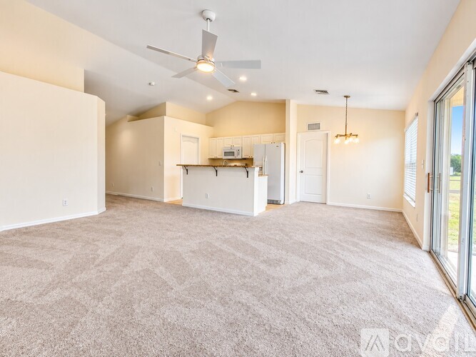 A spacious living room with a carpeted floor and a ceiling fan.