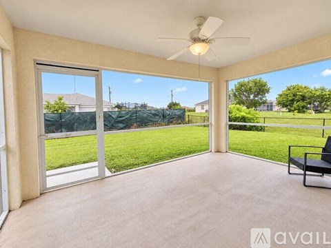 A spacious room with a ceiling fan and sliding glass doors leading to a green lawn.