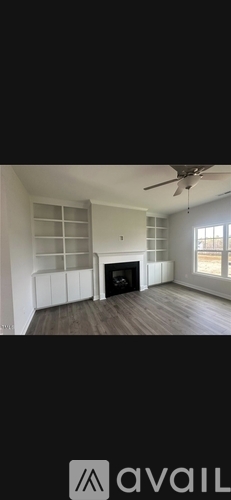 A spacious living room with a fireplace and a ceiling fan.