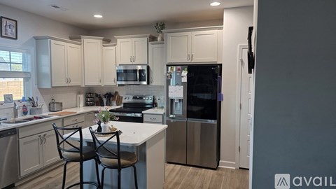 A kitchen with white cabinets and a stainless steel refrigerator.