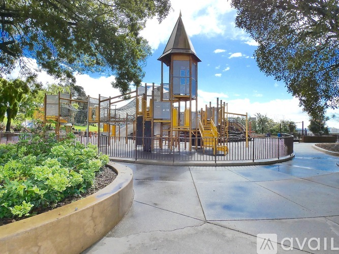 A playground with a wooden tower and yellow stairs.