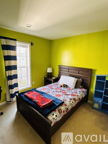 A bedroom with a bed, nightstand, and a window with a striped curtain.