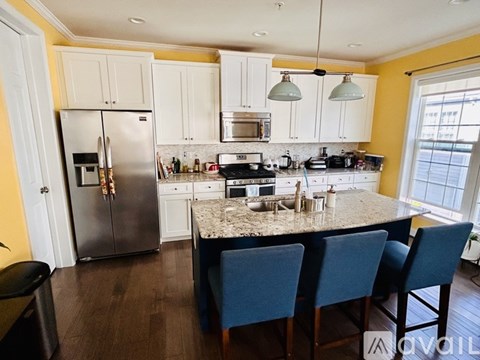 A kitchen with a granite countertop and blue chairs.