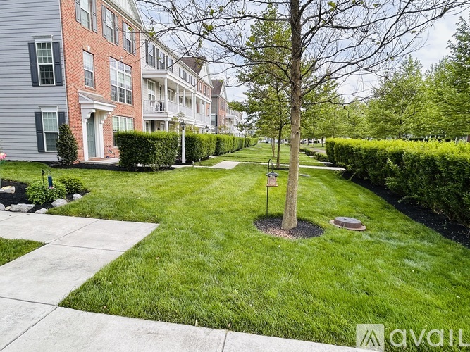 A tree stands in a grassy area in front of apartment buildings.