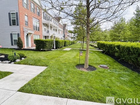 A tree stands in a grassy area in front of apartment buildings.