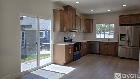 A kitchen with wooden cabinets and stainless steel appliances is available for rent.
