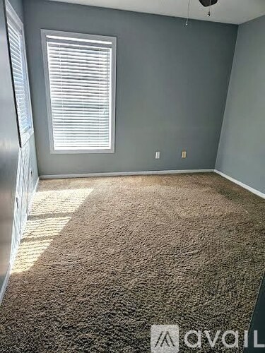 A room with a carpeted floor and a window with blinds.