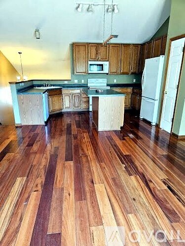 A kitchen with wooden floors and white appliances.