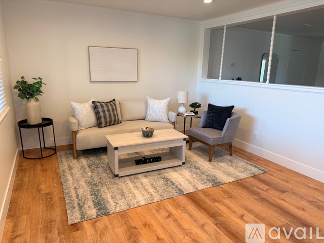 A living room with a white couch, a coffee table, and a chair.