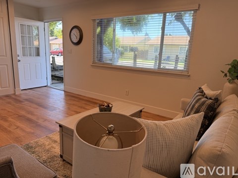 A living room with a couch, a table, and a clock on the wall.