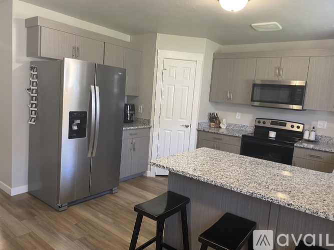 A kitchen with a granite countertop and a stainless steel refrigerator.