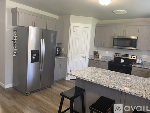 A kitchen with a granite countertop and a stainless steel refrigerator.