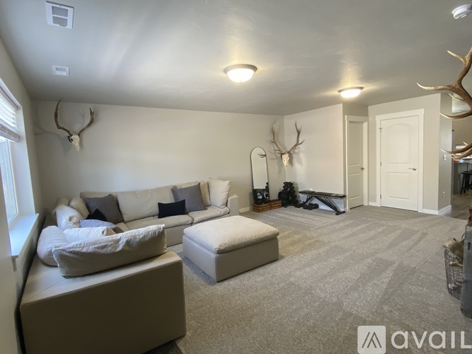 A living room with a white couch and a grey ottoman.