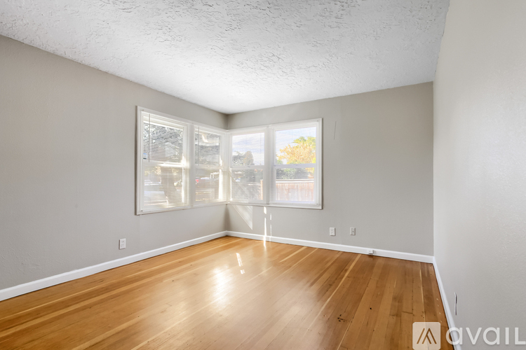 A room with wooden floors and a window showing trees outside.