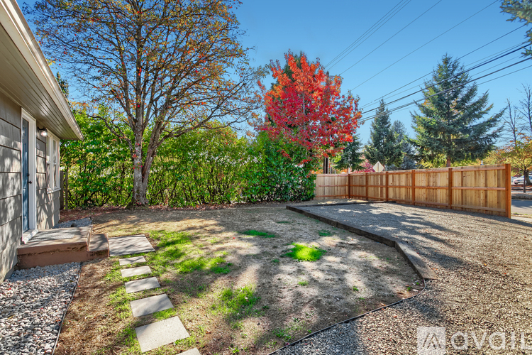 A backyard with a gravel area, a stone path, and a wooden fence.