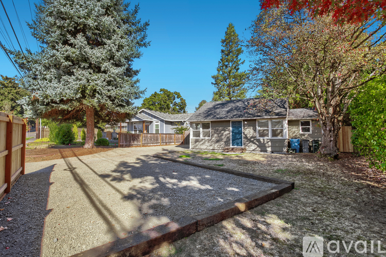 A backyard with a gravel area and a house in the background.