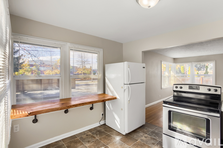 A kitchen with a white refrigerator and stove, a window with blinds, and a window seat.