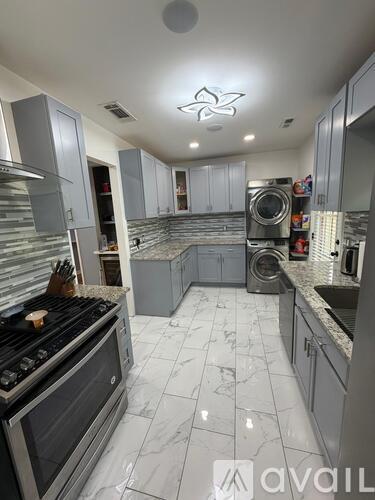 A kitchen with a black stove top oven and a white tiled floor.