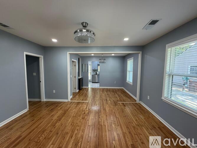 A spacious room with wooden floors and a chandelier.