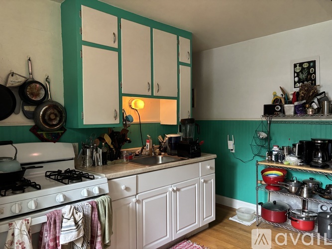 A kitchen with a white stove and green cabinets.