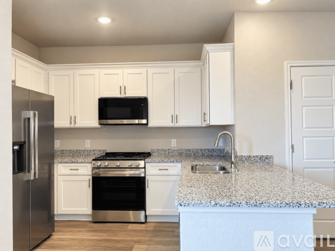A kitchen with white cabinets and a granite countertop.