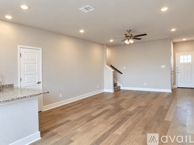 A spacious room with wooden flooring and a ceiling fan.