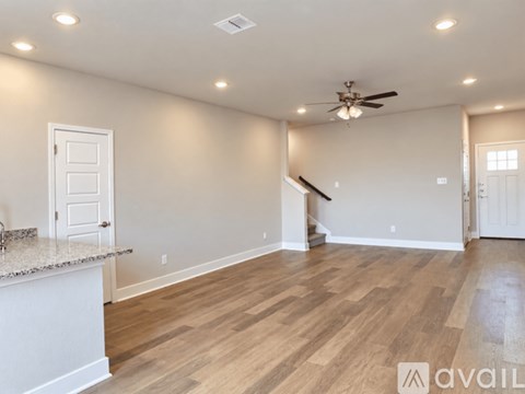 A spacious room with wooden flooring and a ceiling fan.