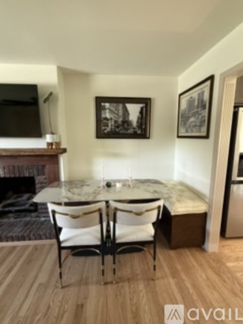 A living room with a fireplace, a dining table with chairs, and pictures on the wall.