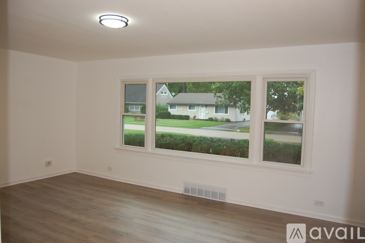 A room with a large window overlooking a residential area.