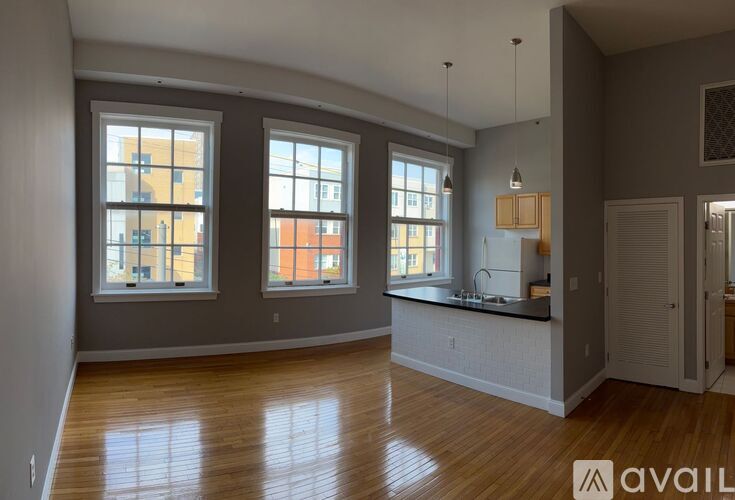 A spacious room with wooden floors and large windows.